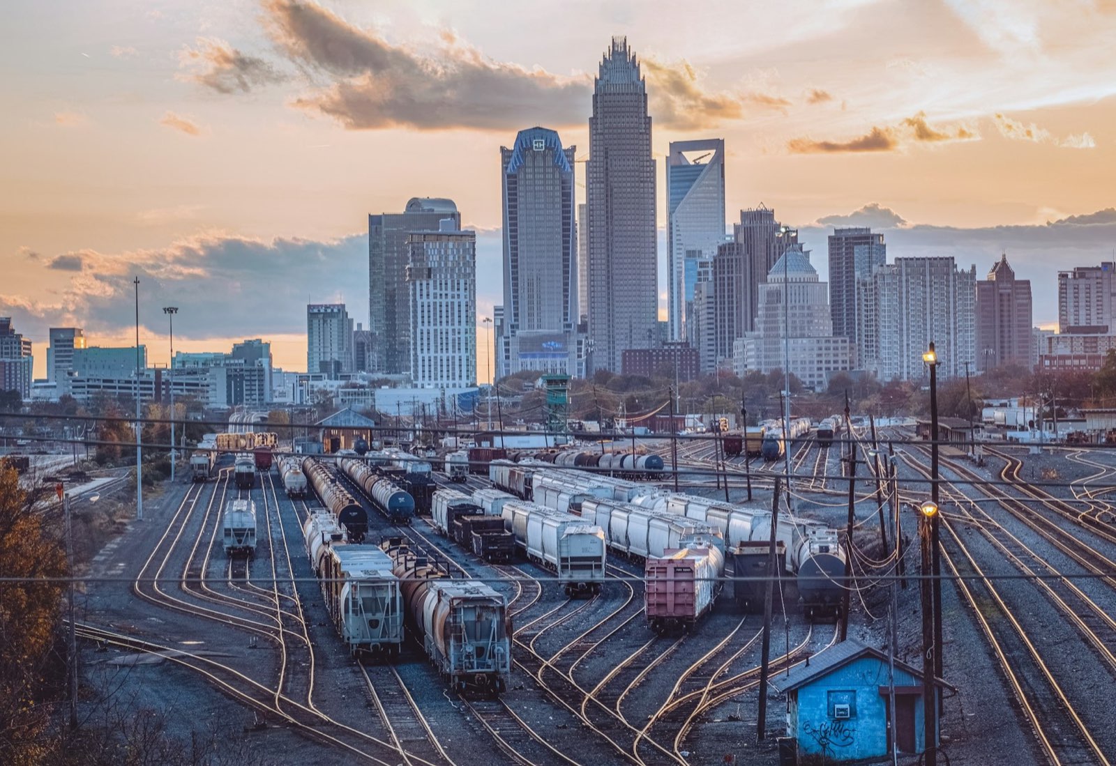 A city skyline at dusk, seen across a rail yard